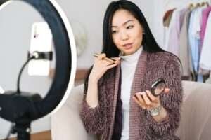 vlogger applying makeup and live streaming with her phone
